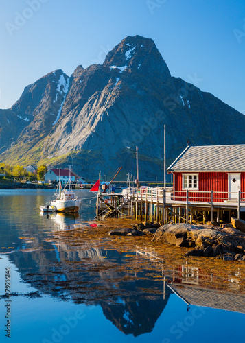 Reine Village on the Lofoten Islands,  Norway. The Typical Norwegian fishing village of Reine under midnight sun,  with the typical rorbu houses.  Mountain In Background photo