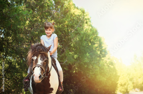 Cute little girl riding pony in park on sunny day © New Africa