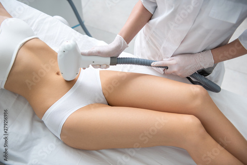 Careful lady on belly laser epilation procedure