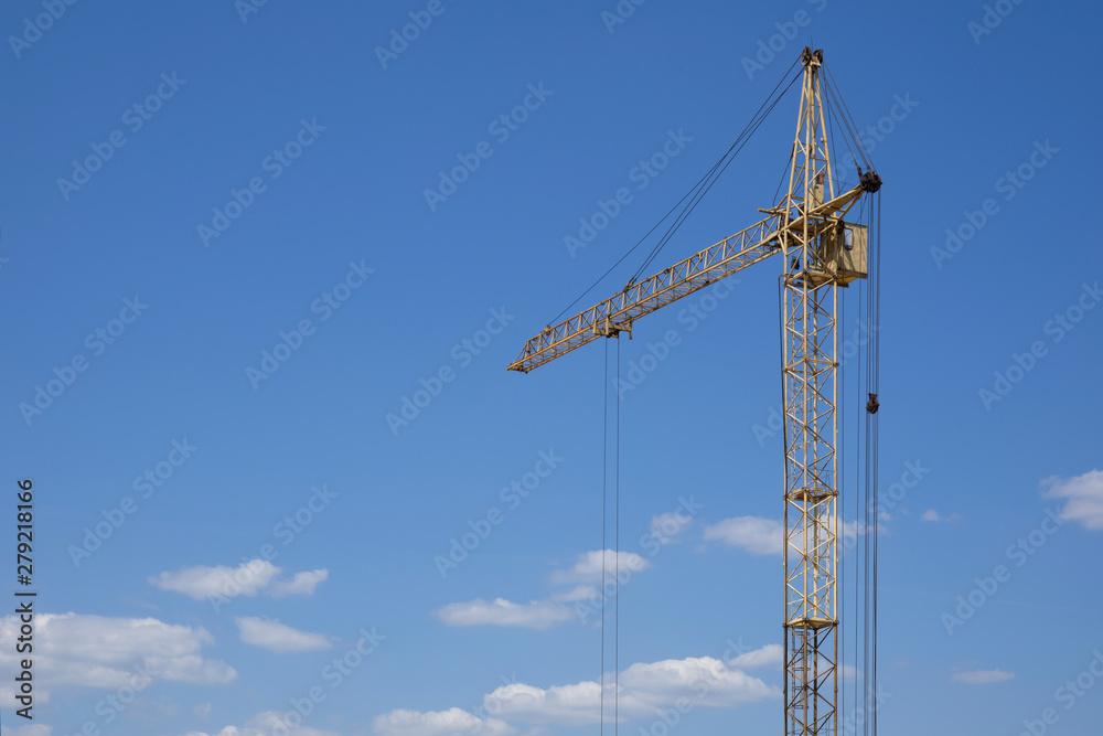 Industrial construction building crane against blue cloudy sky Industrial construction building crane against blue cloudy sky