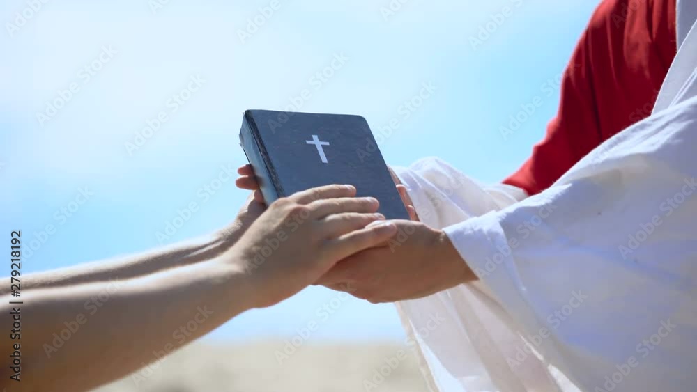 Preacher in robe passing bible to male hands, spreading religious teachings Preacher in robe passing bible to male hands, spreading religious teachings
