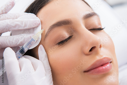 Young lady on procedure of forehead in salon