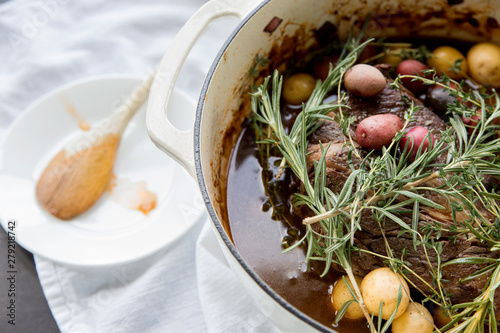 Slika na platnu A close-up view of a roast beef dinner with vegetables and herbs in a dutch ove