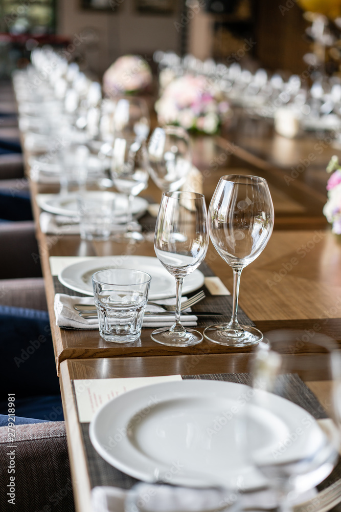 Wine glasses in the foreground. Wedding Banquet or gala dinner. The chairs and table for guests, served with cutlery and crockery.