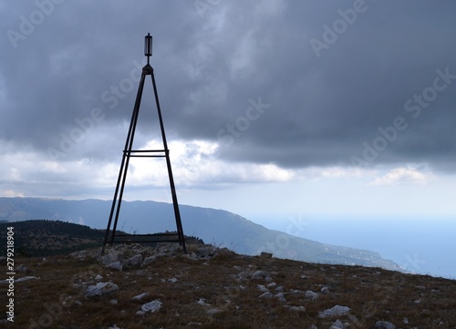 Triangulation point on the mountain overlooking the sea and thunderclouds