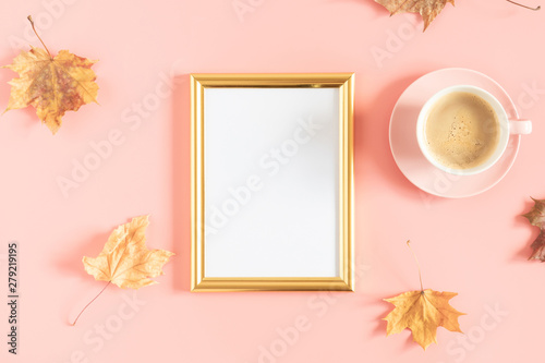 Autumn creative composition. Gold photo frame, dry yellow leaves, cup of coffee on pastel pink background. Fall concept. Autumn background. Flat lay, top view, copy space
