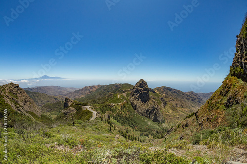 Panoramic view of Tenerife Island with volcano Teide above horizon and Los Roques peaks near Garajonay national park at La Gomera. Thickets of relic laurels and heather on steep green slopes. Canary