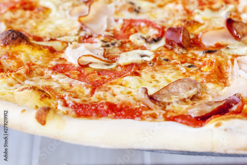 Close-up of Delicious Fresh Pizza with mushrooms, Bavarian sausages, ham