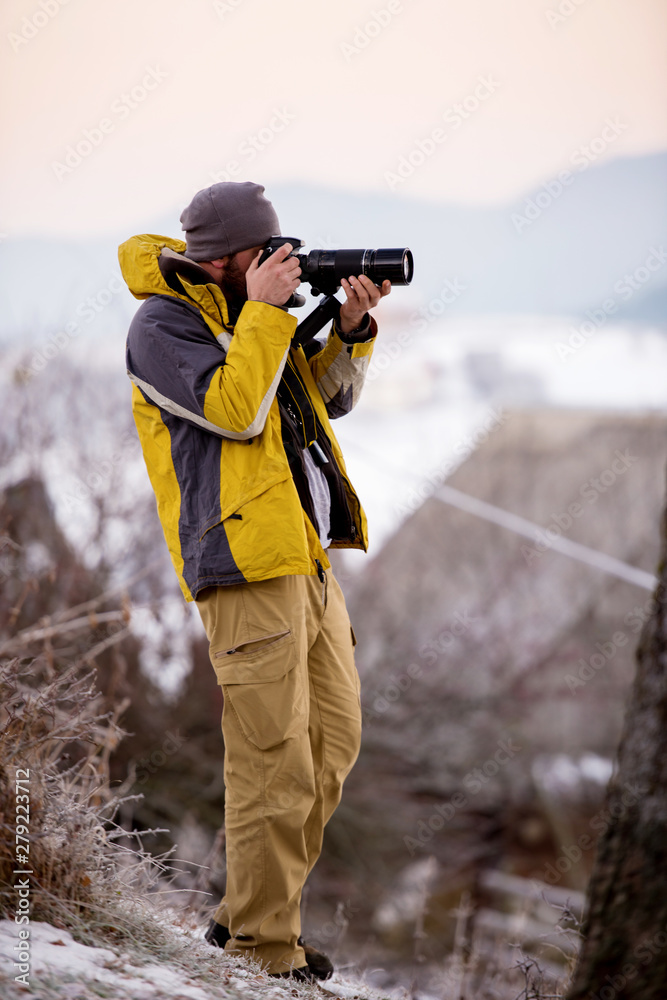 male photographer taking photographs of winter forest