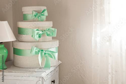 three white boxes of natural fabric stand on each other tied with a green bow stand on a gray surface photo