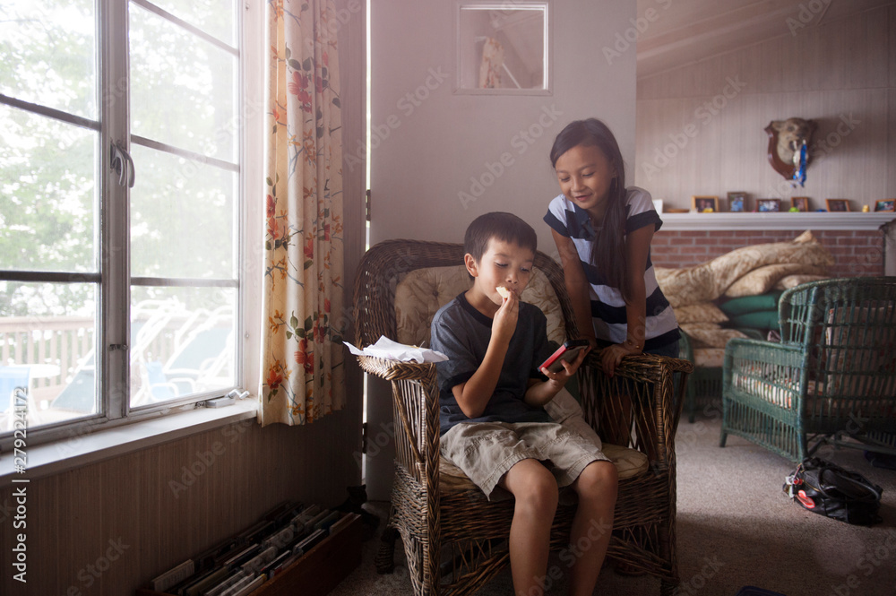 © Cavan for Adobe - Friends (8-9) with smart phone in living room