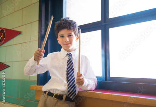School boy (10-11) holding drumsticks in classroom