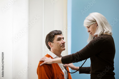 Doctor using stethoscope on patient