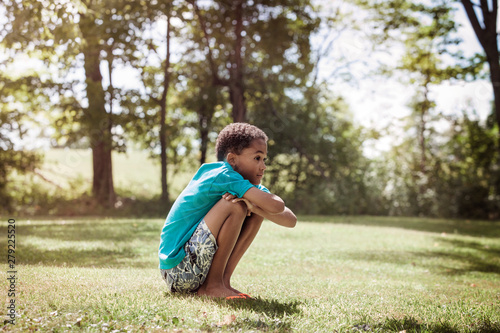Boy (8-9) crouching in field
