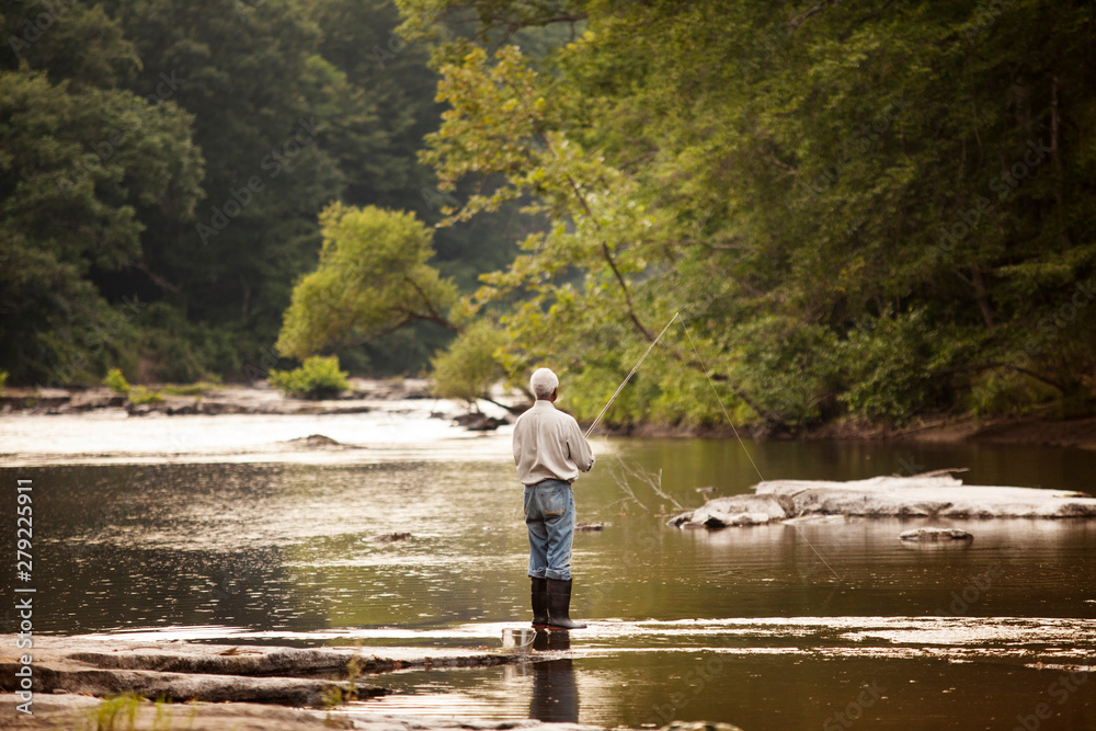 Fototapeta premium Rear view of senior man fishing in river
