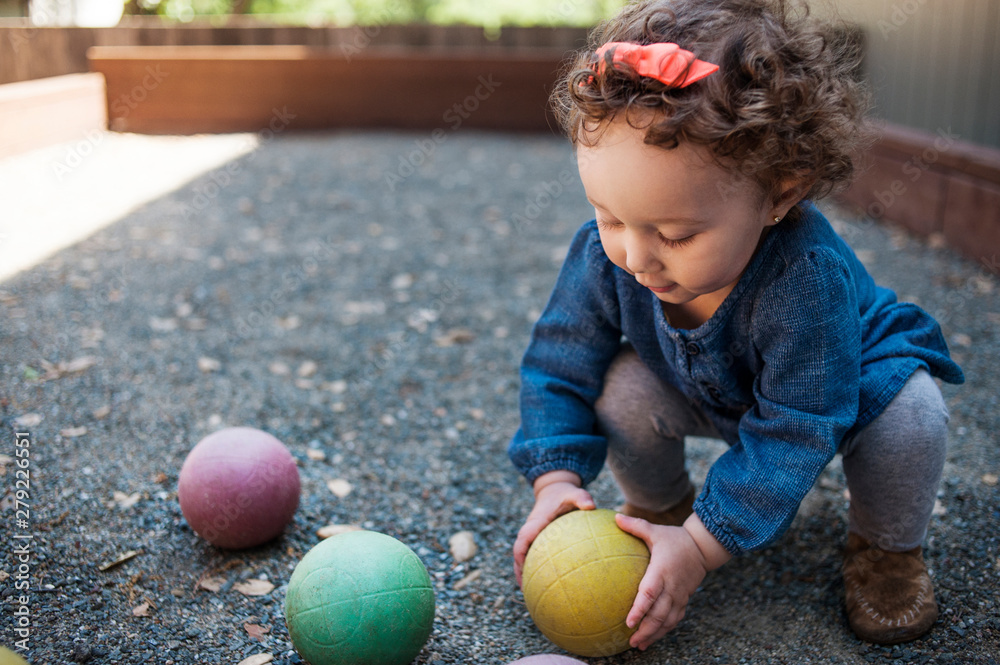 Fototapeta premium Little girl playing with balls outdoors