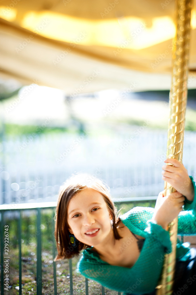 Obraz premium Young girl (8-9) smiling on carousel