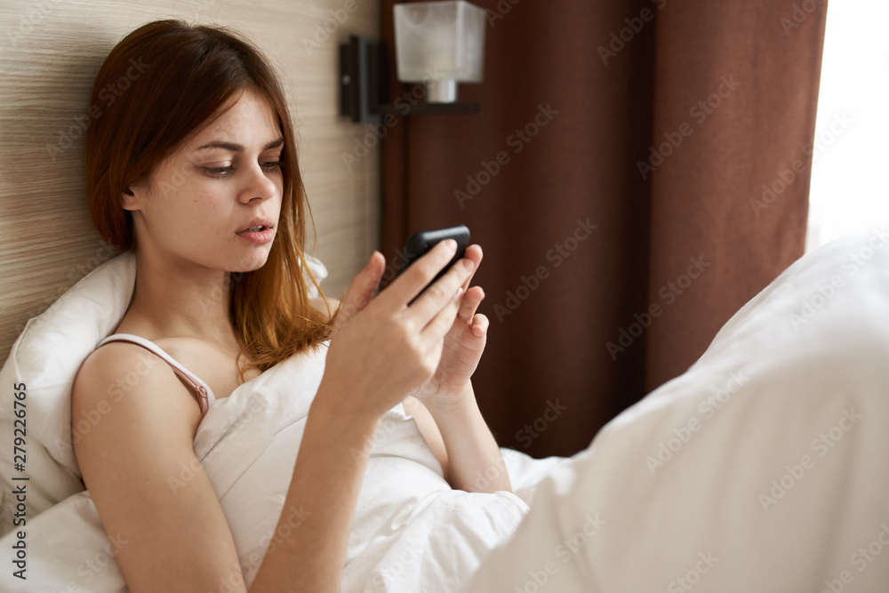 Fototapeta premium woman using mobile phone in bed