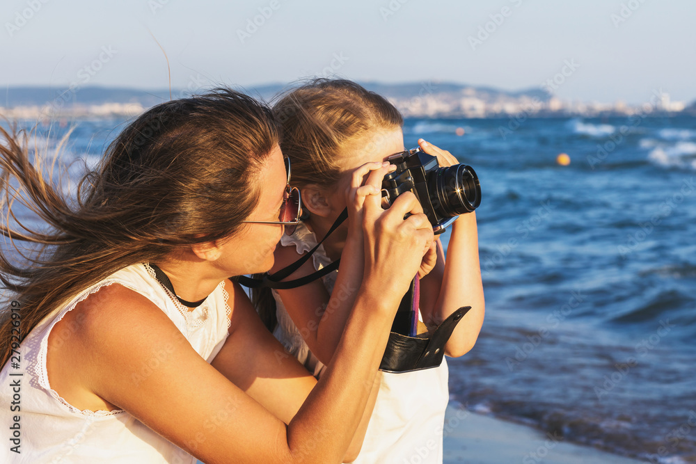 Summer holidays: mother and daughter take pictures of sights while walking near the sea Summer holidays: mother and daughter take pictures of sights while walking near the sea