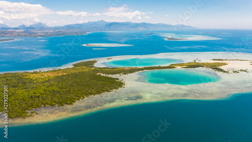 Foto Tropical island with mangroves and turquoise lagoons on a coral reef, top view
