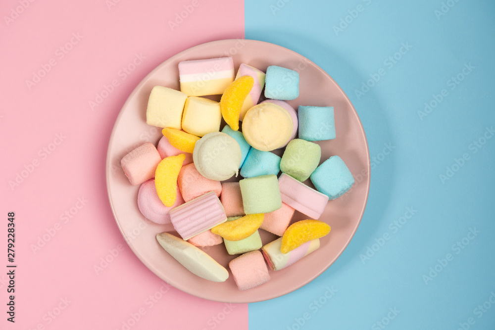 Pink plate with marshmallow, isolated on blue and pink, background. Top view. Pink plate with marshmallow, isolated on blue and pink, background. Top view.