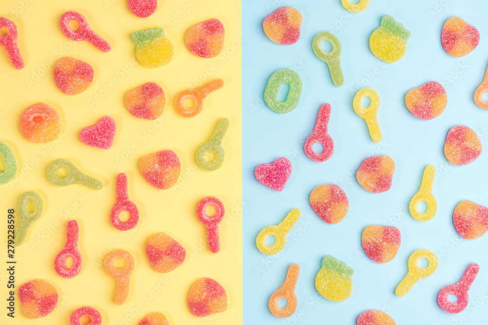 Multicolored gummy candies on yellow and blue backgrounds. Top view.