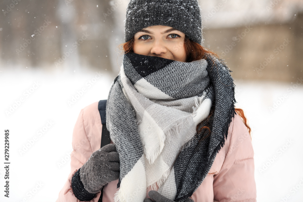 Young cute white caucasian girl in pink down jacket, cap, warm scarf and gloves stands on the street in winter. Young cute white caucasian girl in pink down jacket, cap, warm scarf and gloves stands on the street in winter.