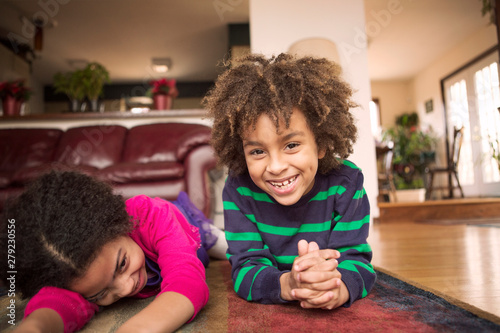 Fotografia Siblings lying on carpet in living room