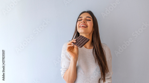  Lovely smiling teenage girl with eyes closed eating chocolate