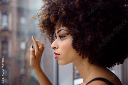 Fotografie Young woman looking through window