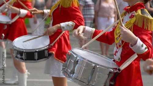 Street performance of festive march of drummers girls in red costumes on city street