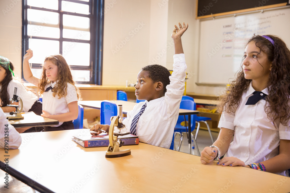 Fototapeta premium Students (8-9, 10-11) raising hands during science class