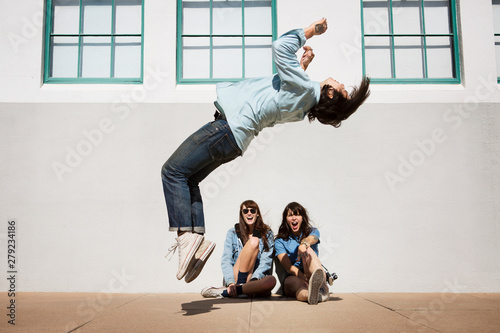 Εκτύπωση καμβά Friends watching man doing somersault outdoors