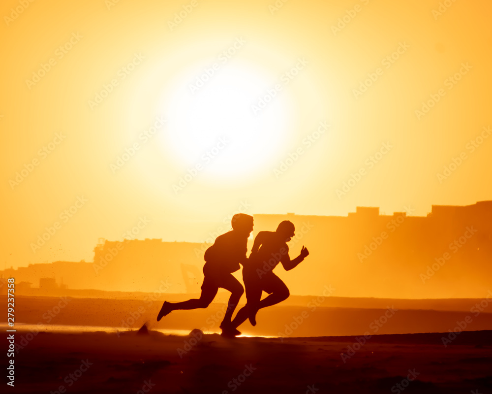 Two silhouettes running into the sunset