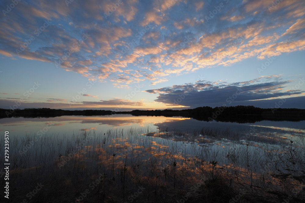 Sunrise and clouds reflected in the calm water of Nine Mile Pond in Everglades National Park, Florida.