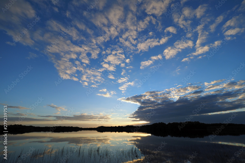 Obraz premium Sunrise and clouds reflected in the calm water of Nine Mile Pond in Everglades National Park, Florida.