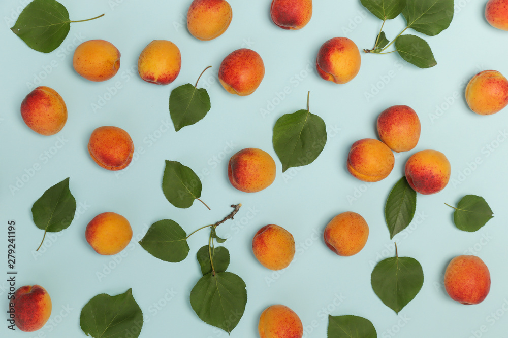 Obraz premium Apricots on a blue background, the flat lay image of ripe apricots and leaves