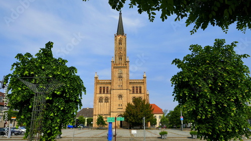 Stadtkirche von Fürstenberg an der Havel vor blauem Himmel umrahmt von grünen Bäumen photo