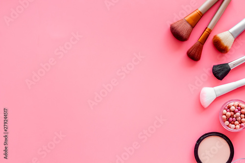 Brushes for make up, blusher and powder on pink visagiste work desk background top view copyspace photo