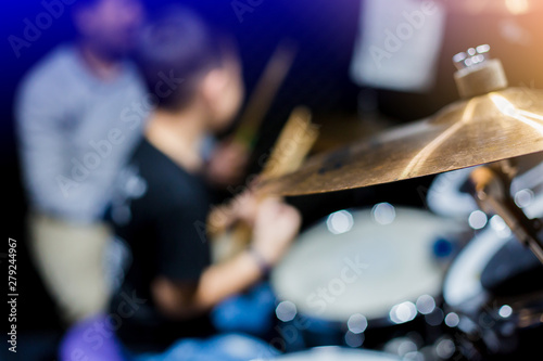 Selective focus to cymbals of drum set with blurry kid learning and play drum set with teacher in music room. The concept of musical instrument.
