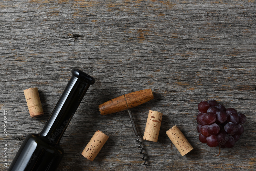 Wine bottle corks, corkscrew and grapes on a rustic old wood table, with copy space at the top