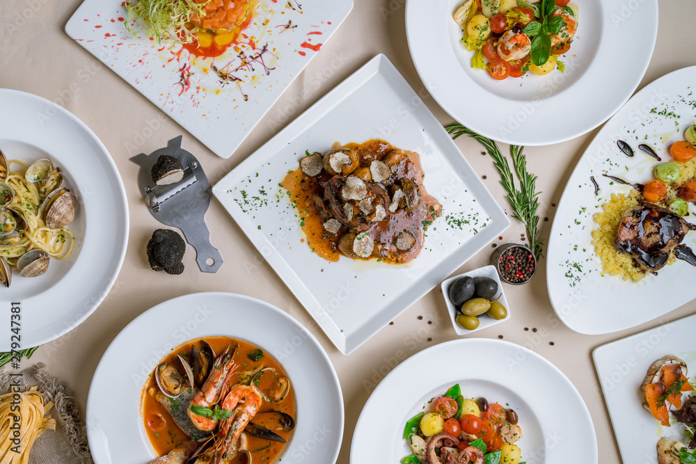 Assorted foodset of European food on table. Seafood casserole bowl, file minion with truffle, vongole, salad with octopus, salad with shrimps Assorted foodset of European food on table. Seafood casserole bowl, file minion with truffle, vongole, salad with octopus, salad with shrimps