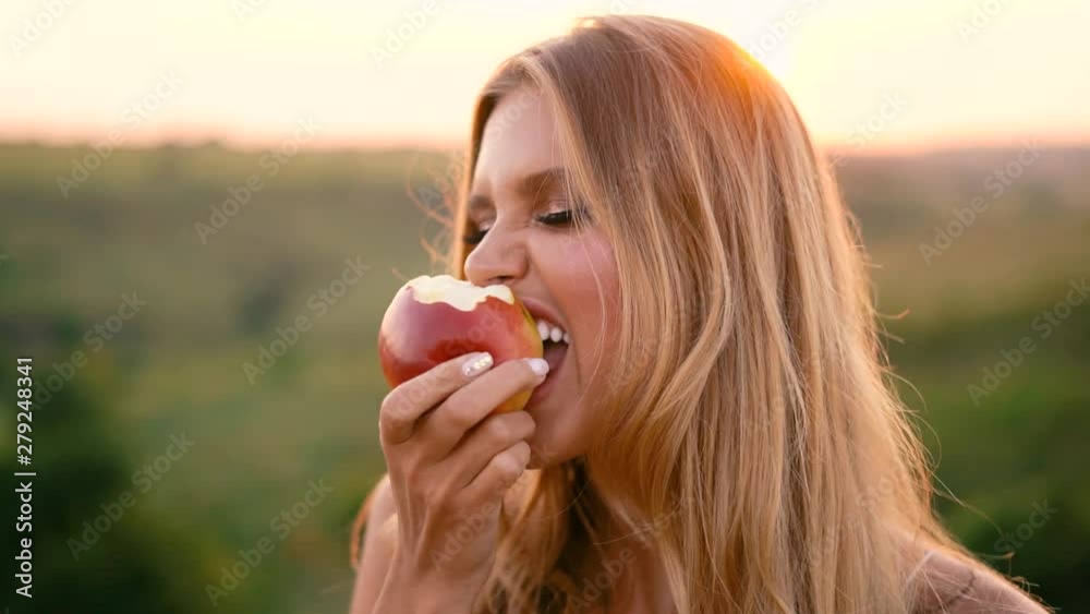 Beautiful sexy blonde girl in white dress posing in a field at sunset with a basket of fruit Beautiful sexy blonde girl in white dress posing in a field at sunset with a basket of fruit