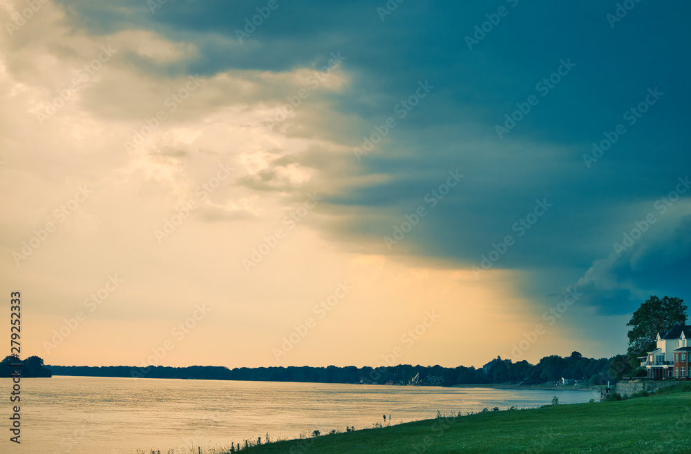 Obraz premium storm approaching riverbank at dusk - wide