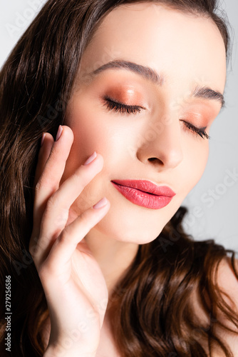 beautiful brunette woman with closed eyes and shiny makeup isolated on grey