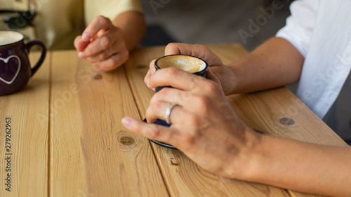 Beautiful female hands hold a cup of coffee in a cafe.