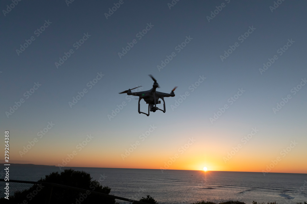 Professional or Prosumer Drone flying over the sea at Sunrise Professional or Prosumer Drone flying over the sea at Sunrise