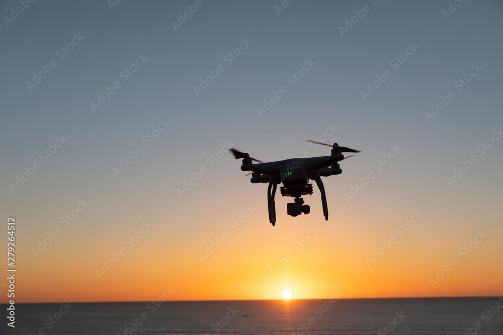 Professional or Prosumer Drone flying over the sea at Sunrise Professional or Prosumer Drone flying over the sea at Sunrise
