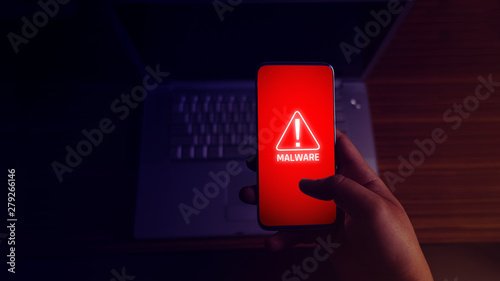 An anonymous hacker and uses a malware with mobile phone to hack password the personal data and money from Bank accounts. The concept of cyber crime.