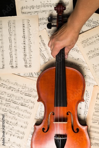 Hand Holding Violin On Music Sheets Close-up